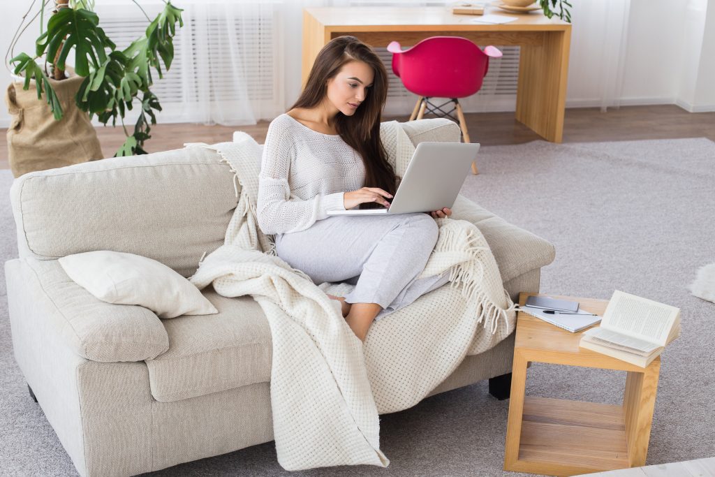 This image has an empty alt attribute; its file name is woman-using-laptop-while-sitting-at-the-sofa-at-home-1024x683.jpg